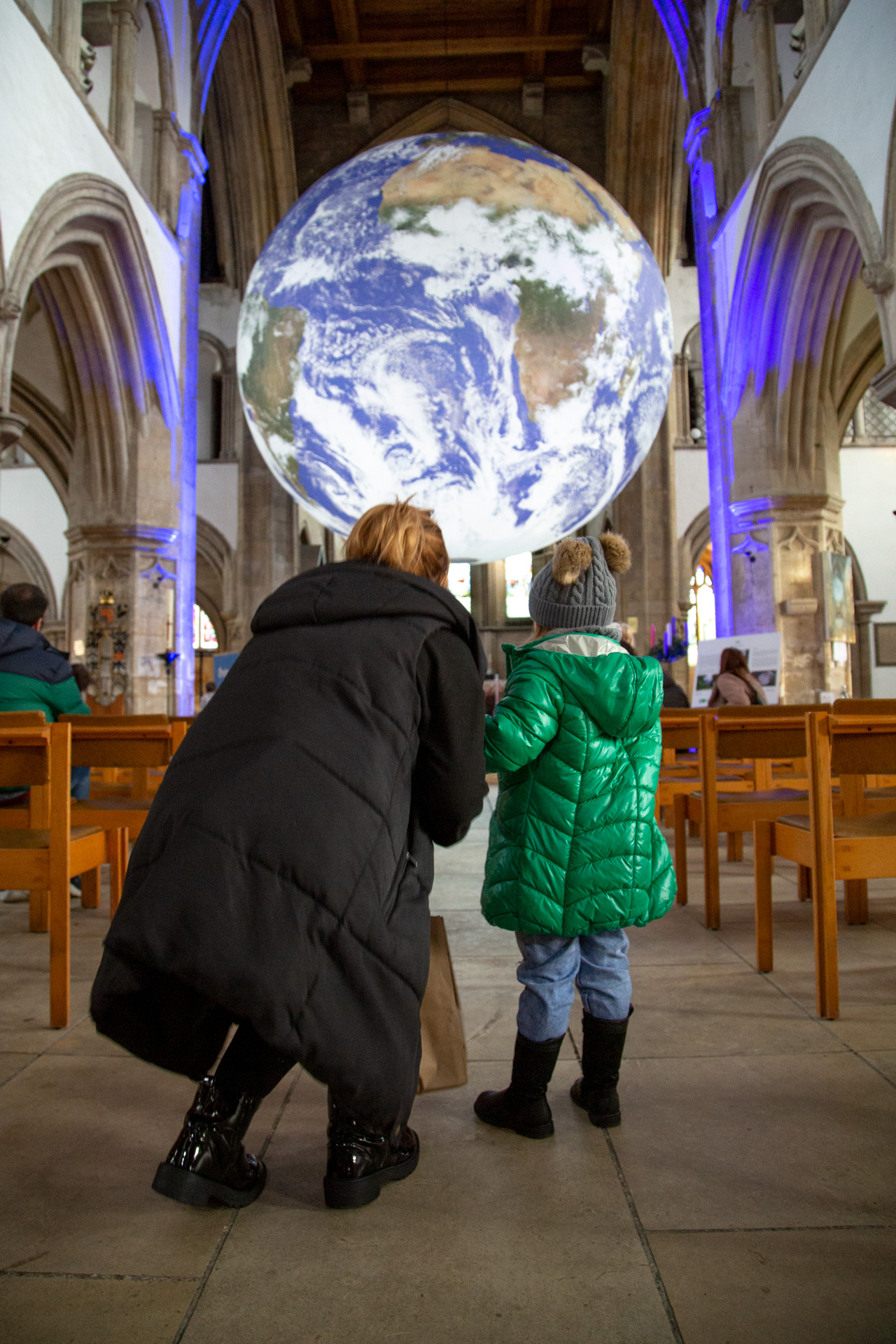 A woman and child looking at a large exhibit of the Earth in a church